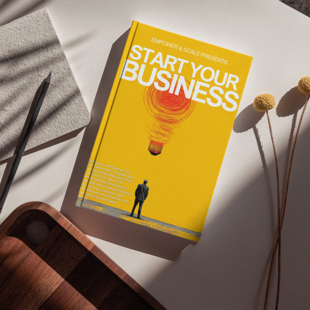 Book titled 'Start Your Business' on a table with a pen and notebook.